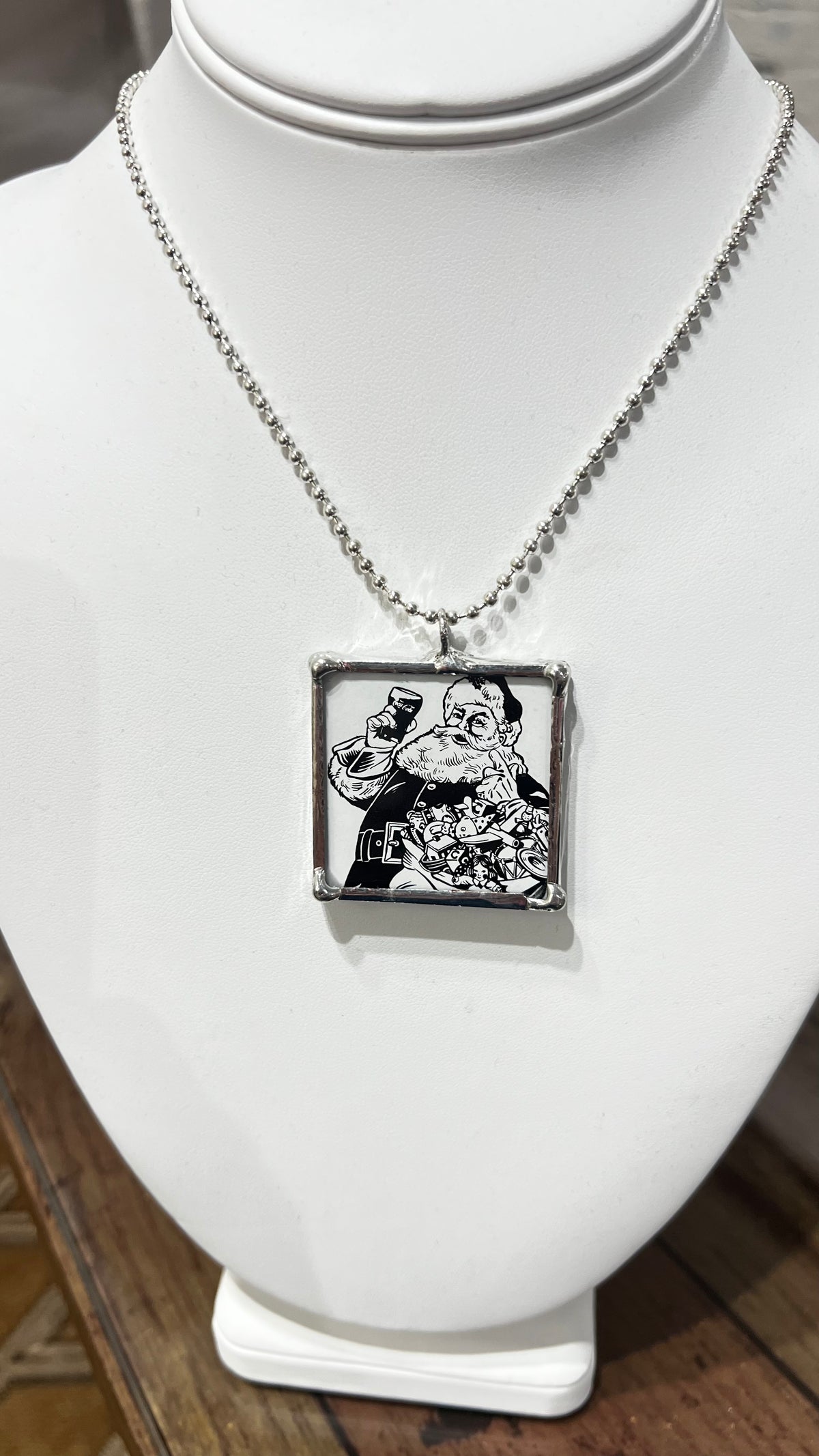 Necklace with a pendant featuring a black and white illustration on a white mannequin bust.